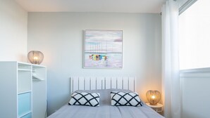 A bedroom with a bed, two bedside lamps, a wardrobe, and a wall-mounted painting. - Port Arcachon by Interhome (Arcachon)