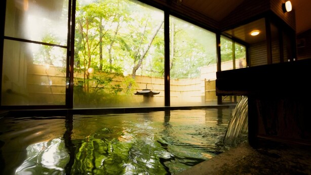 Un baño de aguas termales con vistas a árboles a través de amplios ventanales.