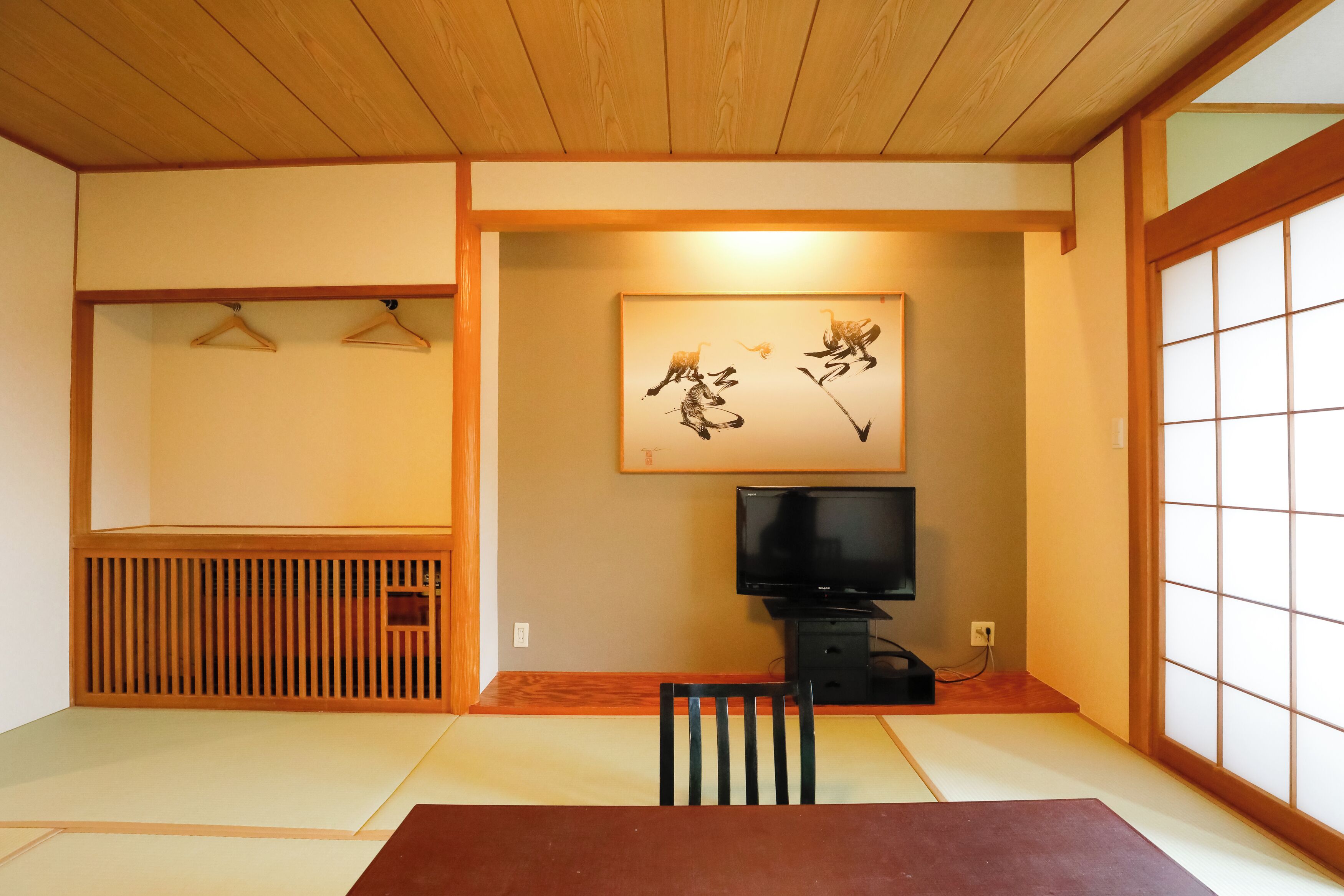 A traditional Japanese room with tatami flooring, a television, a wooden cabinet, and a shoji screen.