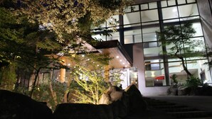 Un edificio moderno con amplios ventanales y un camino de piedra que conduce a la entrada.