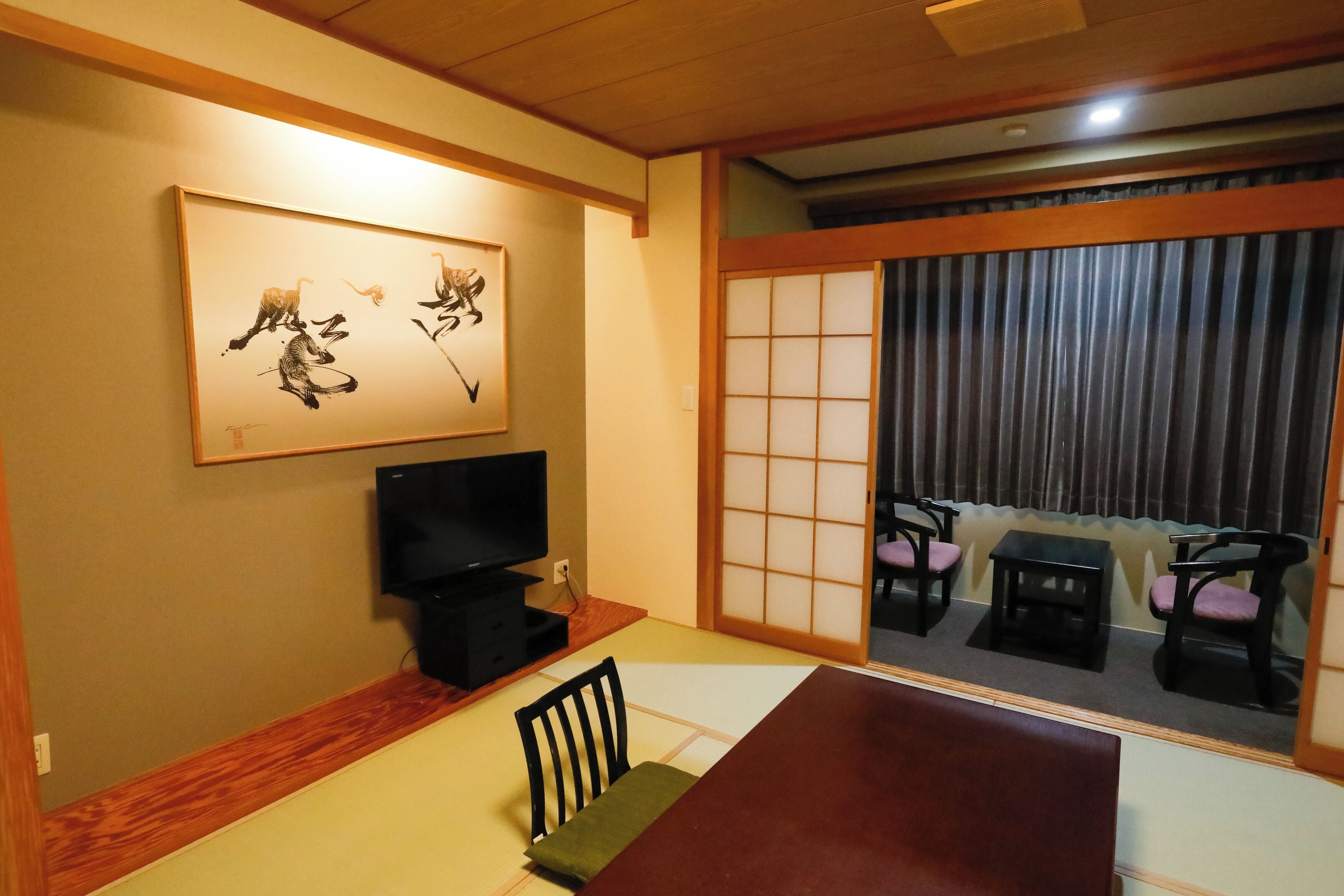 Una habitación de estilo japonés tradicional, con suelo de tatami, una mesa baja y un televisor.