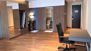 Una camera moderna con pavimento in legno, una scrivania, una sedia, un armadio e uno specchio.
