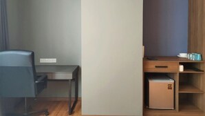 Una stanza compatta con scrivania, sedia e un piccolo armadietto.