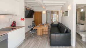 Un espacio habitable compacto con kitchenette, comedor y zona de estar.