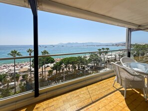 A balcony with a view of the beach and sea, white wicker furniture, and a tiled floor. - Three Bedroom Sea View-ORS7 (CANNES)