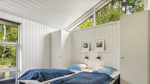 Une chambre avec deux lits, une fenêtre et une vue sur les arbres.