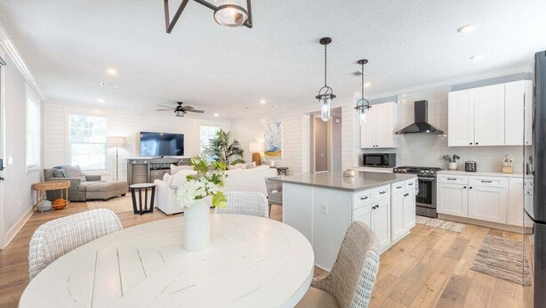 A modern kitchen with white cabinetry, a central island, and a dining area with a round table.
