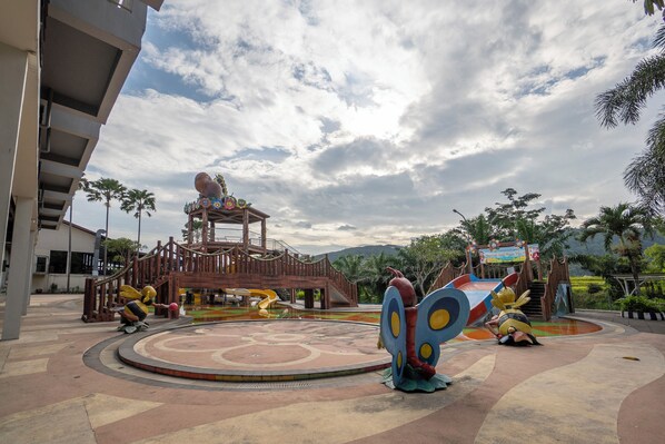 A playground with slides and a large butterfly sculpture.