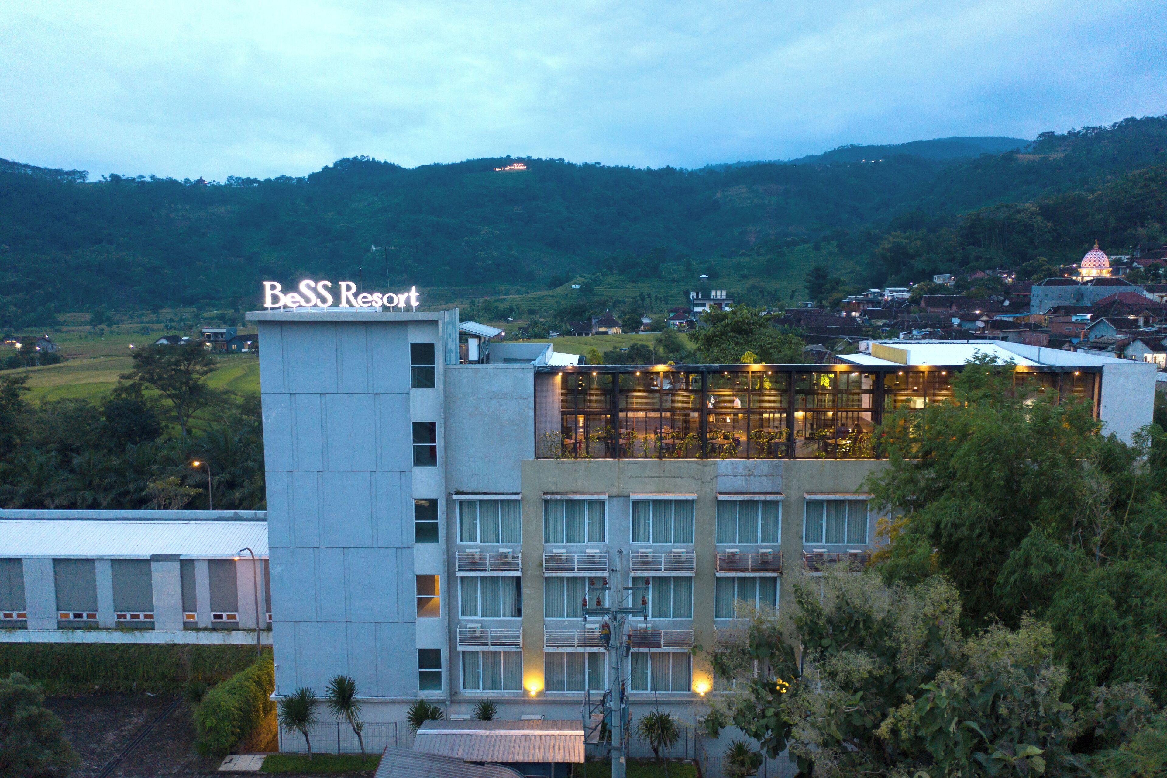 A hotel with a sign reading "BESS Resort," featuring a modern architectural design with multiple floors and balconies.