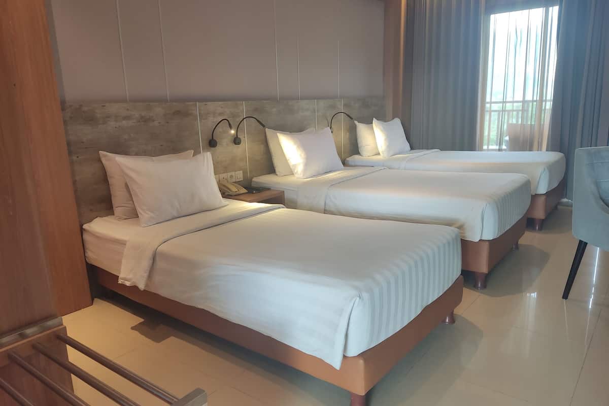 Habitación de hotel con dos camas, un cabecero de madera, una mesita de noche con teléfono y una ventana con cortinas.