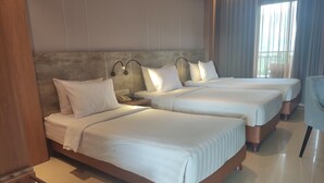 A hotel room with two beds, a wooden headboard, a nightstand with a phone, and a window with curtains.