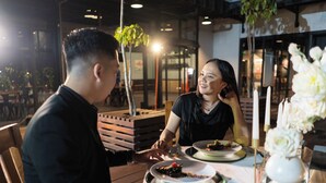 A restaurant setting with a table set for two, featuring plates with food and a candle centerpiece.