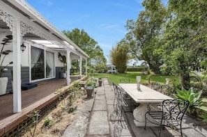 Enjoy meals or relaxation in a tranquil setting surrounded by lush greenery and a shaded pergola.