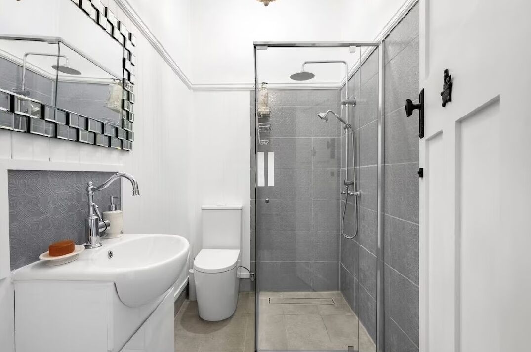 A modern bathroom with a white sink, toilet, and glass-enclosed shower.