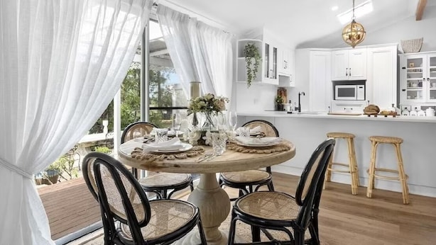 A dining area with a round table set for four, surrounded by wicker chairs. - The Dawning Farmhouse (Jaspers Brush)