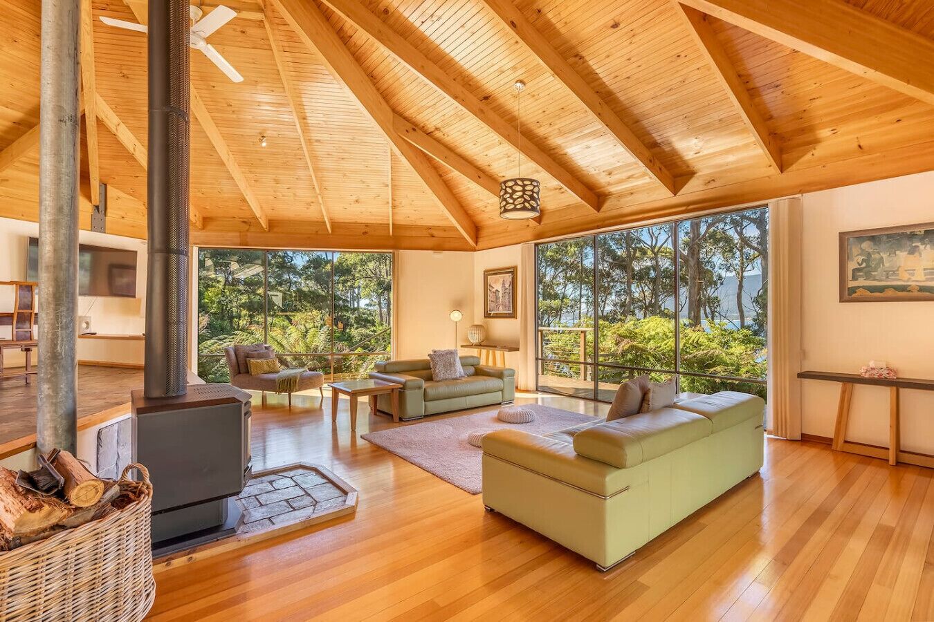 A spacious living room with a large wooden ceiling, a fireplace, and a view of the outdoors.