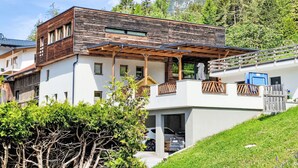 A modern two-story house with a wooden facade, a covered porch, and a view of a mountainous landscape. - Sandra Falch by Interhome (Flirsch)