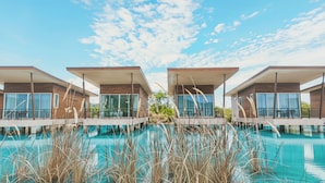 Een modern hotel met gebouwen van twee verdiepingen, een zwembad en een helderblauwe lucht.