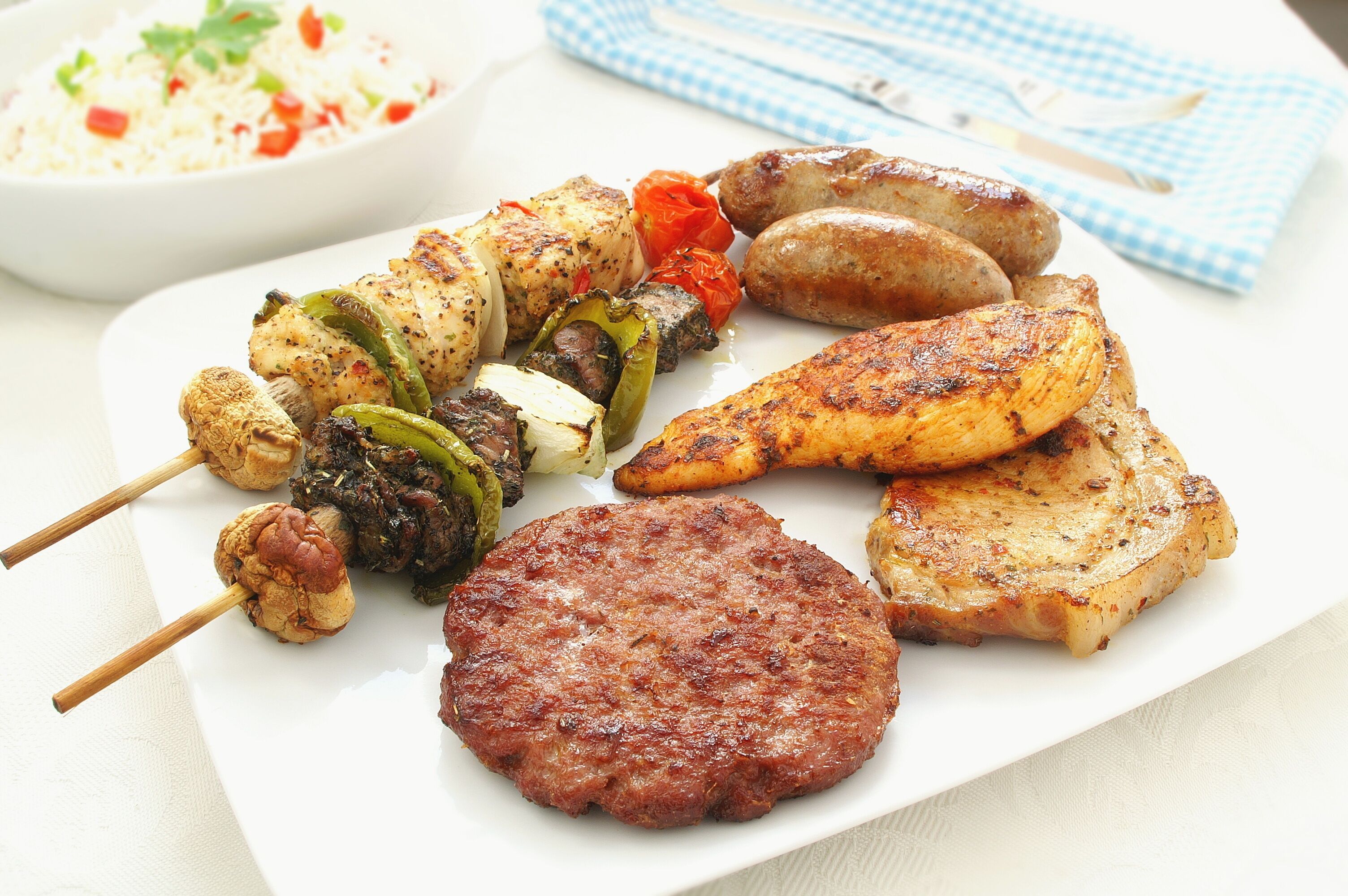 A plate of grilled meat, sausages, and vegetables.