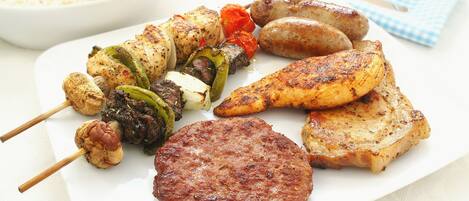 A plate of grilled meat, sausages, and vegetables.