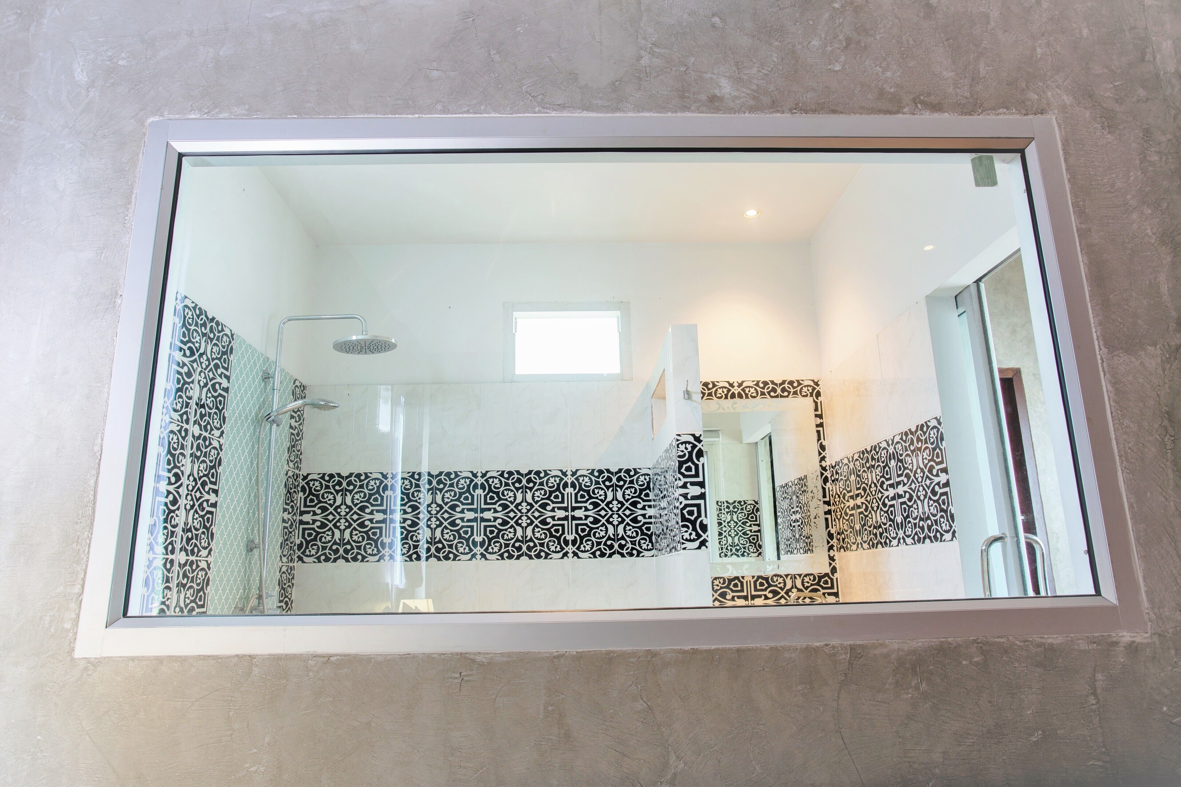 A bathroom with patterned tiles, a shower, and a mirror.