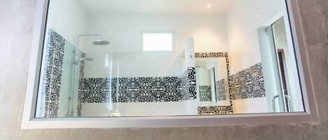 A bathroom with patterned tiles, a shower, and a mirror.