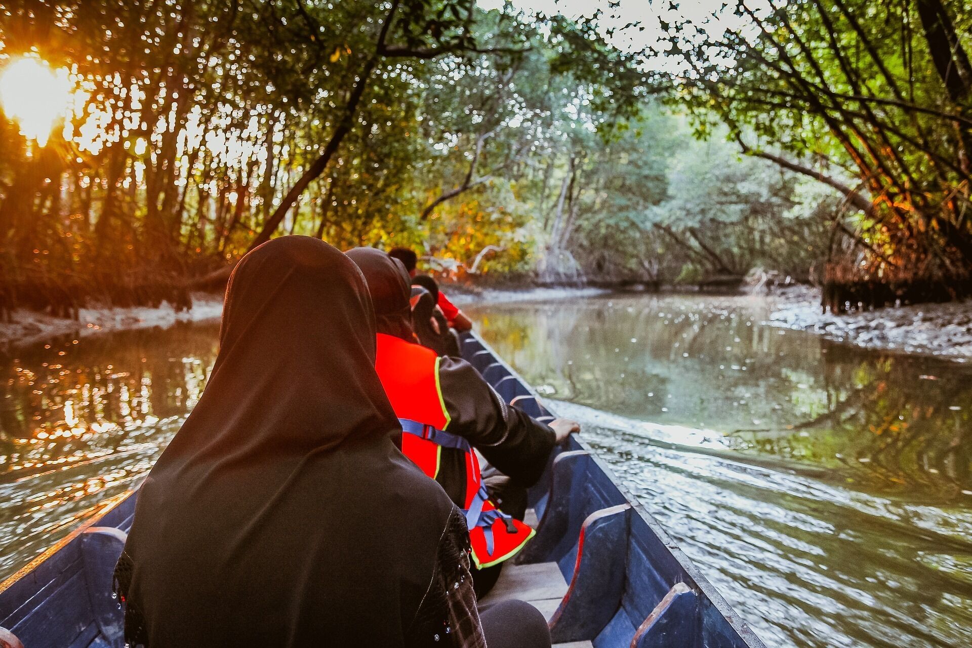 A person in a boat on a calm river surrounded by trees.