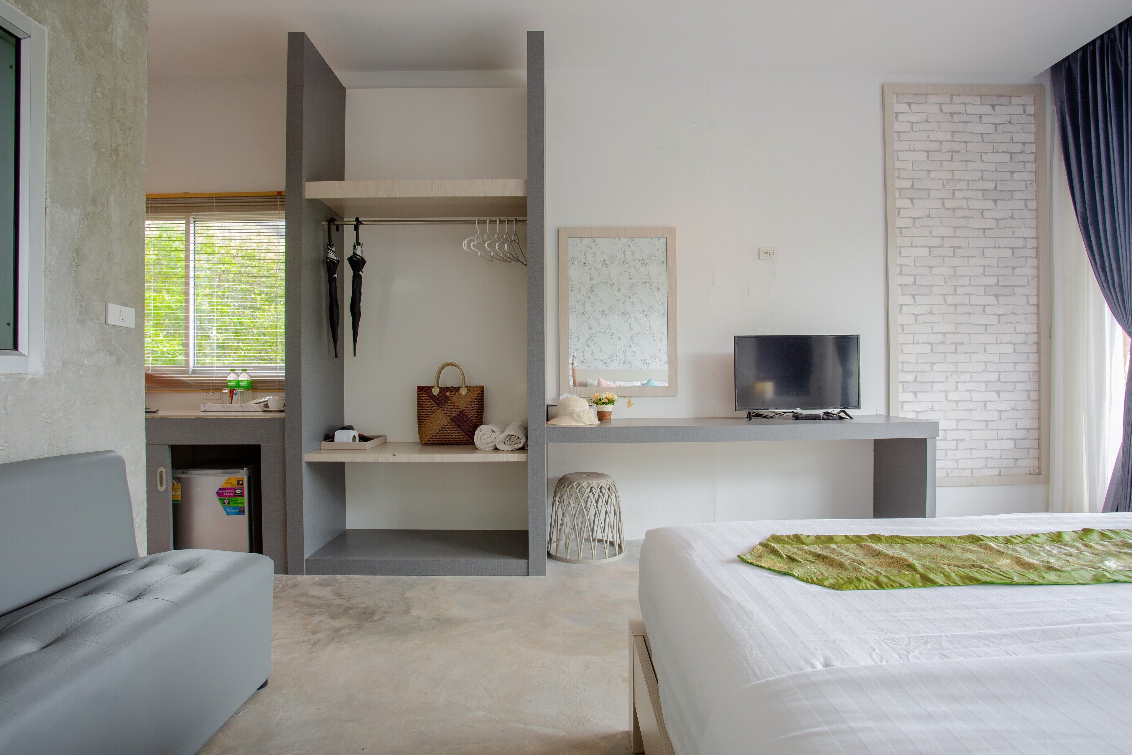 Una habitación de hotel moderna con cama, escritorio, televisor y ventana con persianas.
