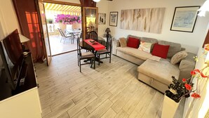 Uma sala de estar com sofá, mesa de jantar e televisão.