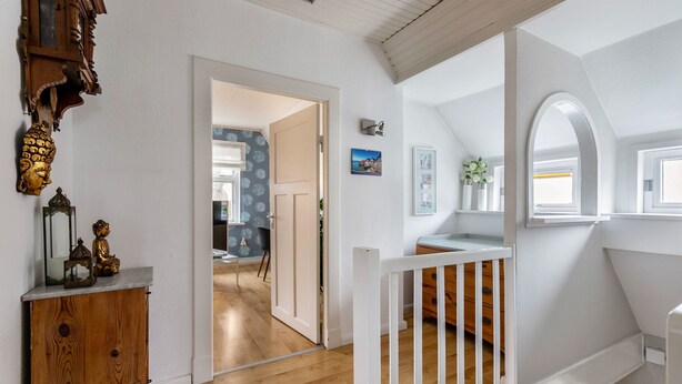 A room with a wooden floor, white walls, a white railing, and a door leading to another room. - Apartment "Schwennautal" with Private Garden & Wi-Fi (Glücksburg)