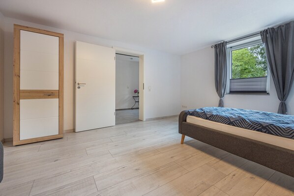 Una camera da letto con un letto, un armadio e una finestra con tende.