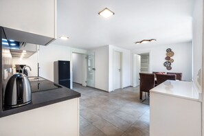 Eine moderne Küche mit Wasserkocher, Kühlschrank und einer Essecke mit Stühlen und Tisch.