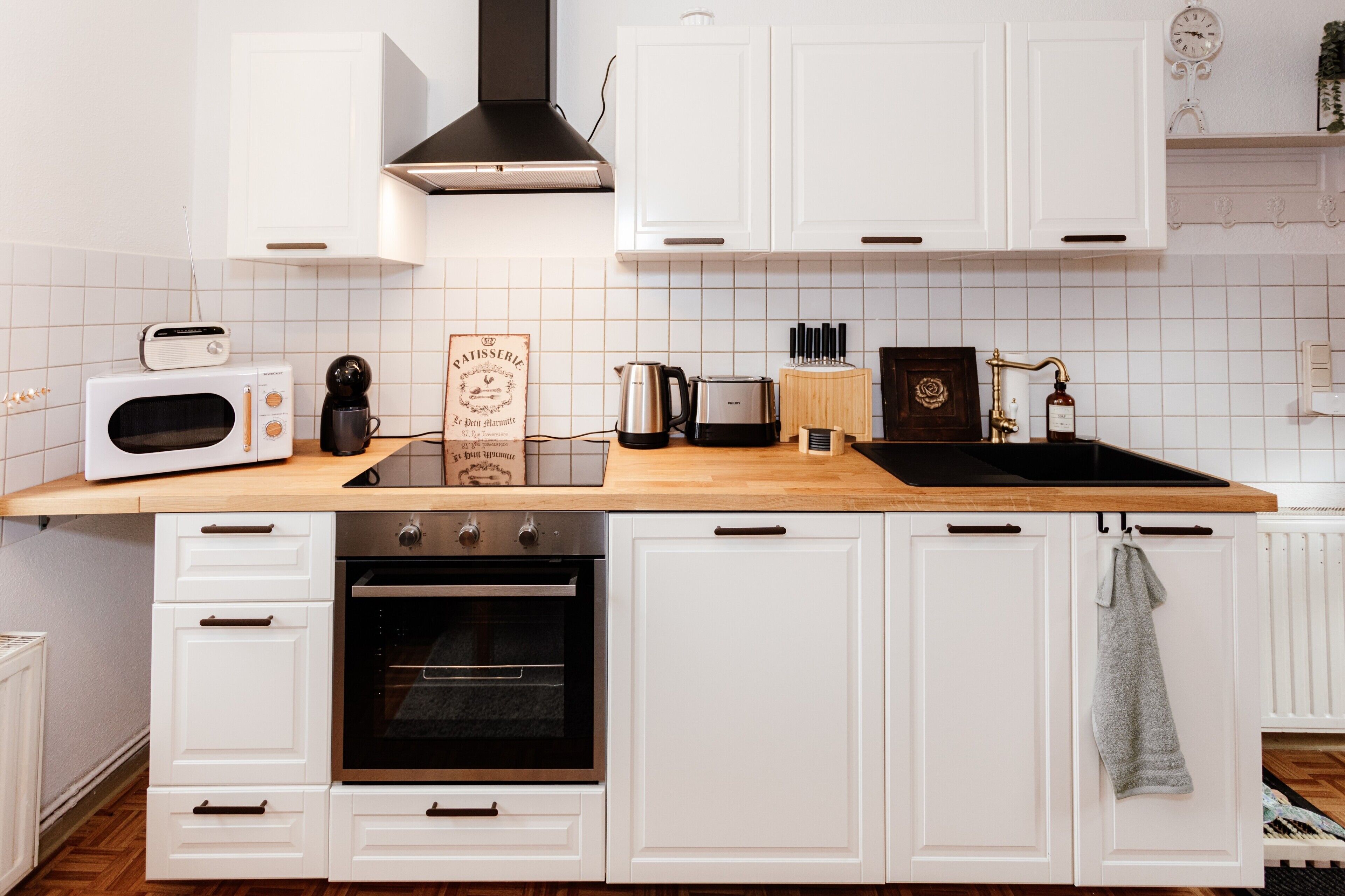 Uma cozinha com armários brancos, micro-ondas, torradeira e pia.