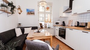 Una cucina moderna con mobili bianchi, un piano di lavoro in legno e un'area pranzo con tavolo e sedie.