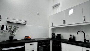 A modern kitchen with white cabinets, a black countertop, a skylight, and a patterned rug. - Studio Apartment 'Lorenz' with Wi-Fi (Olching)