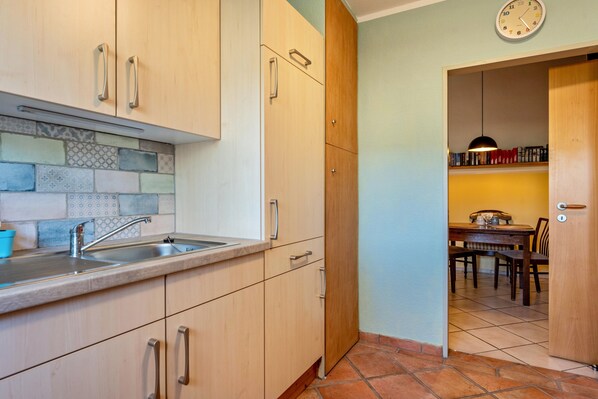 A kitchen with a tiled backsplash, a sink, and wooden cabinets.