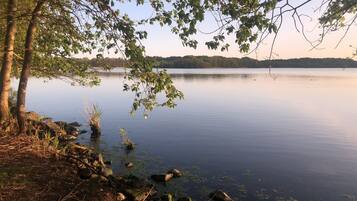 A calm lake with trees and rocks along the shore.