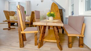 Comedor con muebles de madera, un jarrón con flores y vistas al exterior.