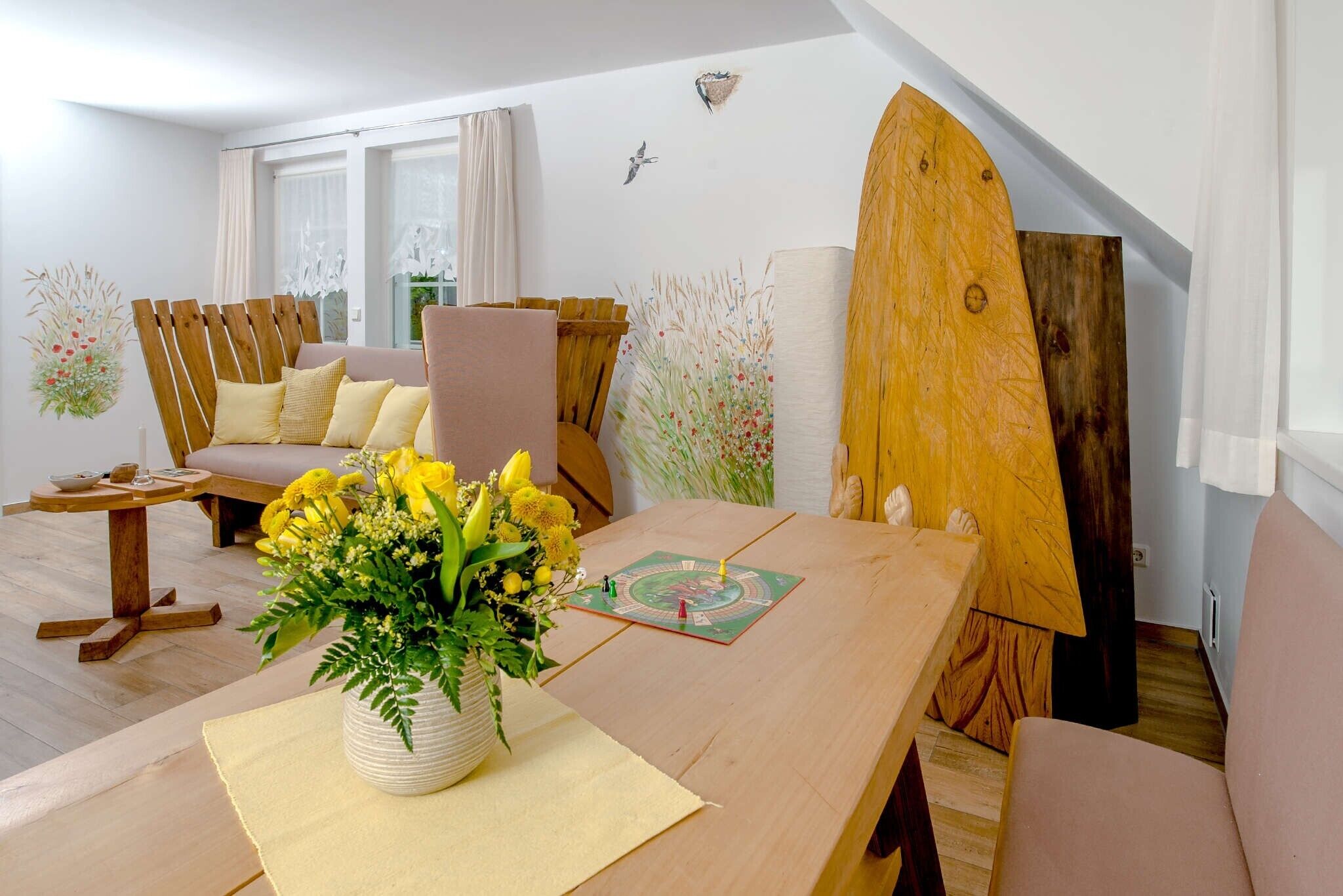 Un salon chaleureux avec une table en bois, un canapé et une planche de surf appuyée contre le mur.