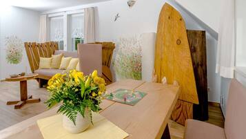 Un salon chaleureux avec une table en bois, un canapé et une planche de surf appuyée contre le mur.