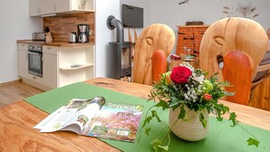 Una cocina moderna con estufa, una mesa de comedor con una revista y un florero con flores.