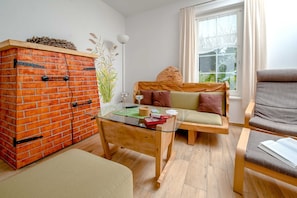 A cozy room with a brick cabinet, a glass-top table, a sofa with cushions, and a chair.