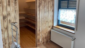 Ein Zimmer mit einer Holzwand, einem Fenster mit Jalousien, einem Heizkörper und einer Metallleiter.