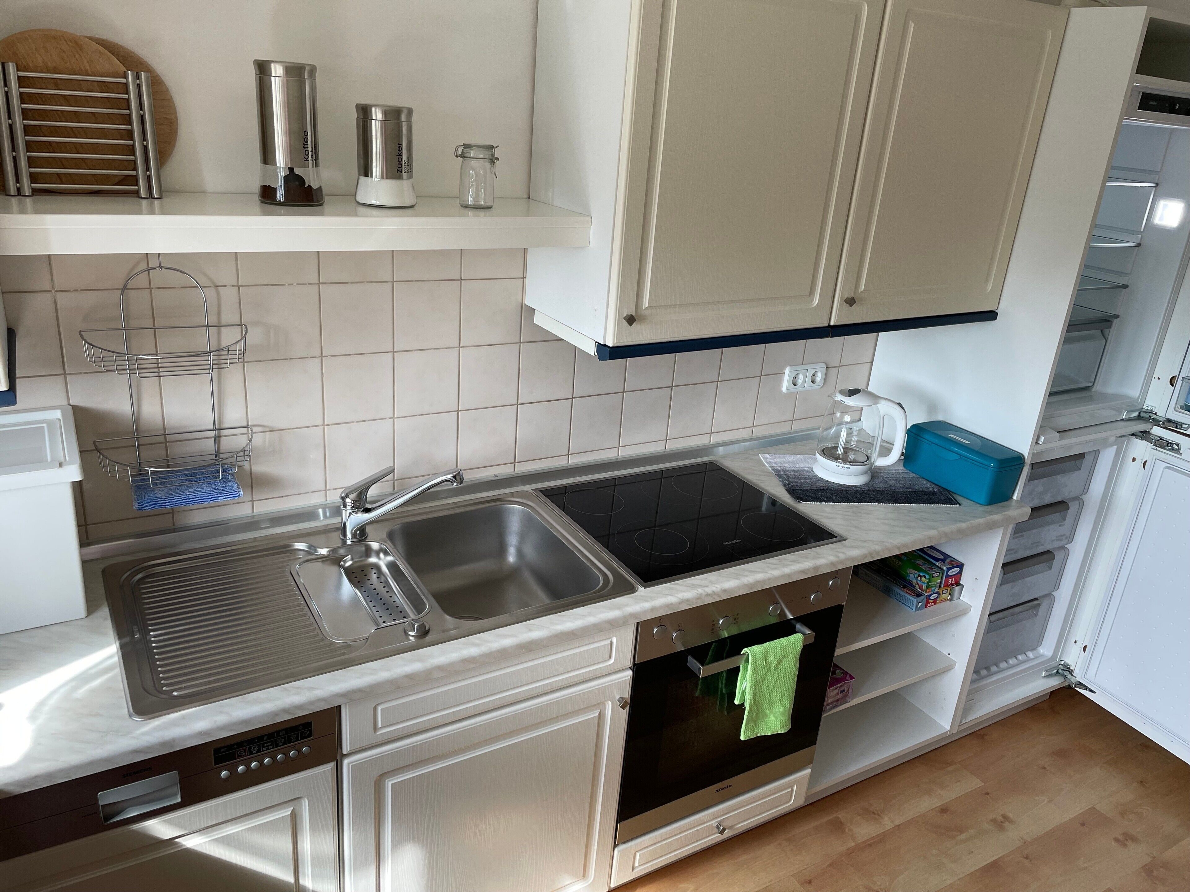 A modern kitchen with a stainless steel sink, a built-in oven, and a coffee maker on the countertop.