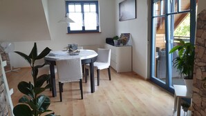 Ein Essbereich mit einem runden Tisch, Stühlen, einem Fenster und Blick ins Freie.