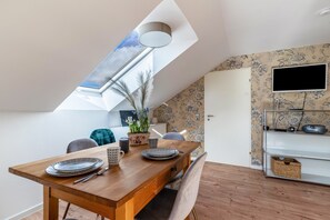 Un coin repas avec une table en bois, des assiettes et une plante en pot.