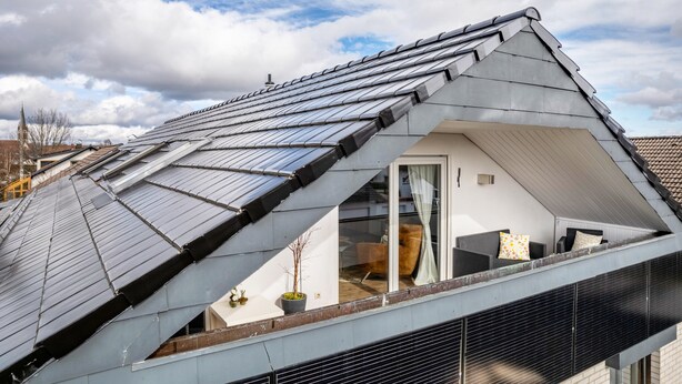 Una habitación moderna en el ático, con techo inclinado, tragaluces y vista al cielo.
