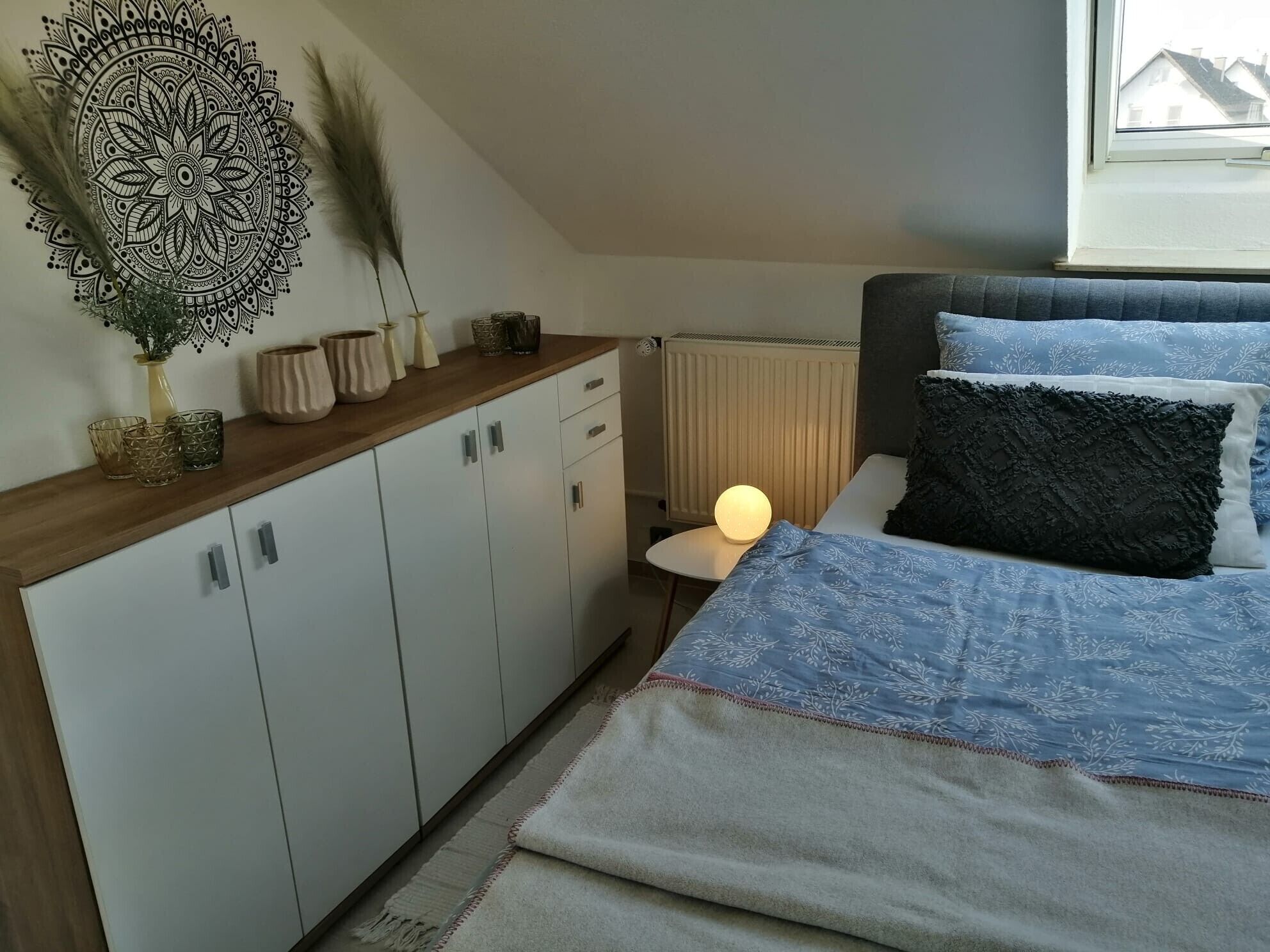 A bedroom with a bed, bedside table, lamp, and decorative wall art.