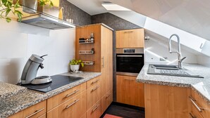 Una cocina moderna con encimeras de granito, gabinetes de madera, horno empotrado y cafetera.