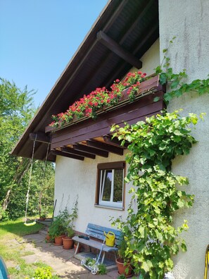 A house with a wooden balcony, a window, and potted plants.